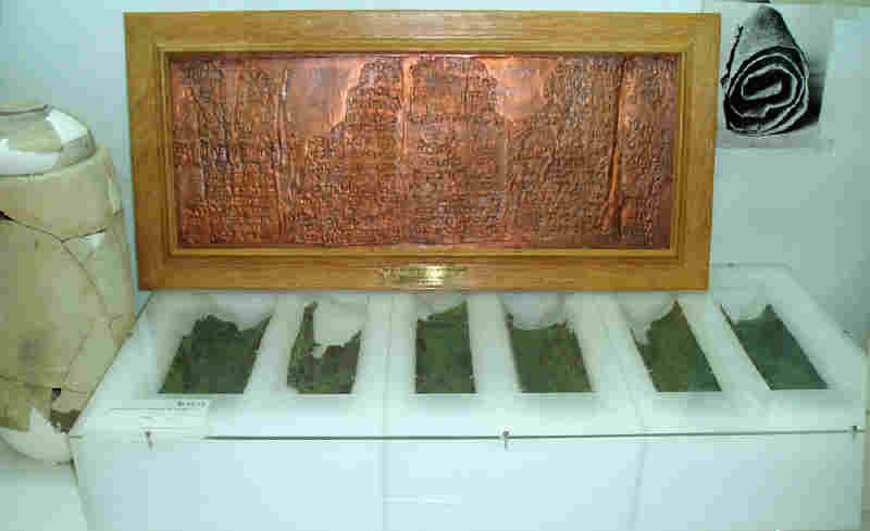 The Copper Scroll, currently on display at the Archaeological Museum in Amman, Jordan. To the left the Scroll Jar; in the background the Framed Replica of the Copper Scroll; in the foreground the original Copper Scroll cut into fragments; in the upper right a Photograph of the rolled Copper Scroll. Source: www.sdnhm.org